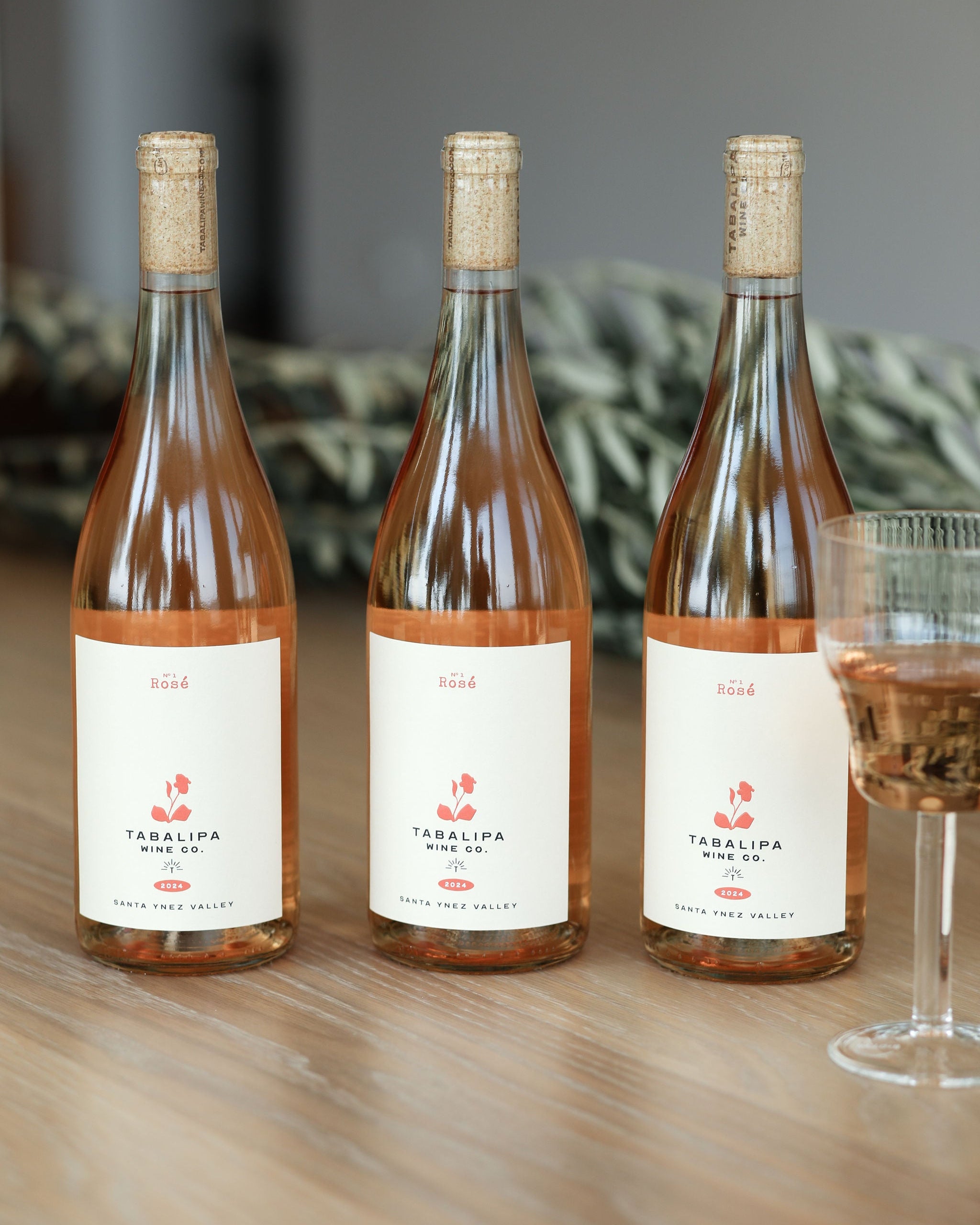 Three bottles of Tadepaliga wine on a wooden table with a blurred background