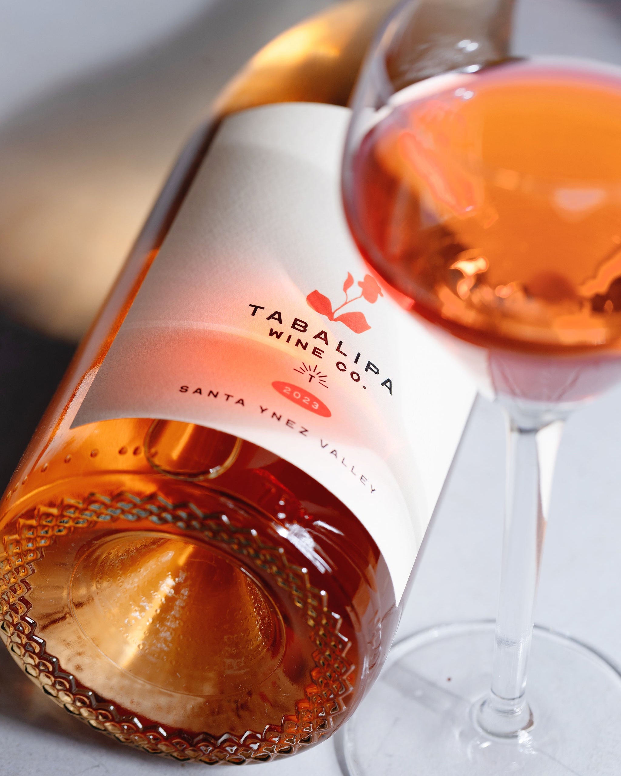 Tabalipa wine bottle and glass with rose wine on a light background