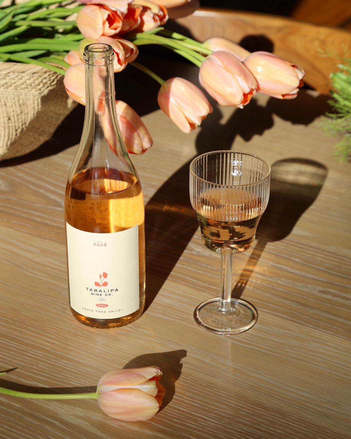 Tabalipa Nº1 Rosé wine bottle in outdoor vineyard setting with glass or rosé to the right of the bottle.